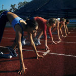Four Female Athletes (18-21) in Starting Blocks Awaiting the Race Start Four Female Athletes (18-21) in Starting Blocks Awaiting the Race Start