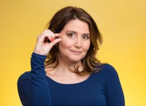 31160090 - closeup portrait, young middle aged woman, showing small amount gesture with hands, isolated yellow background. human emotion facial expression feeling, body language, sign, symbol, reaction, perception